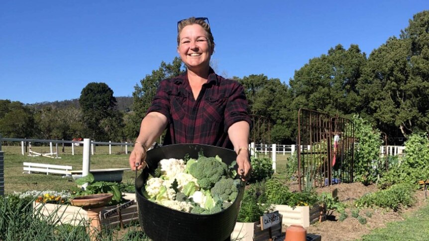 Perri Chaplin posing with a bucket of vegetables in the garden in a story about how gardening can help cancer survivors heal.