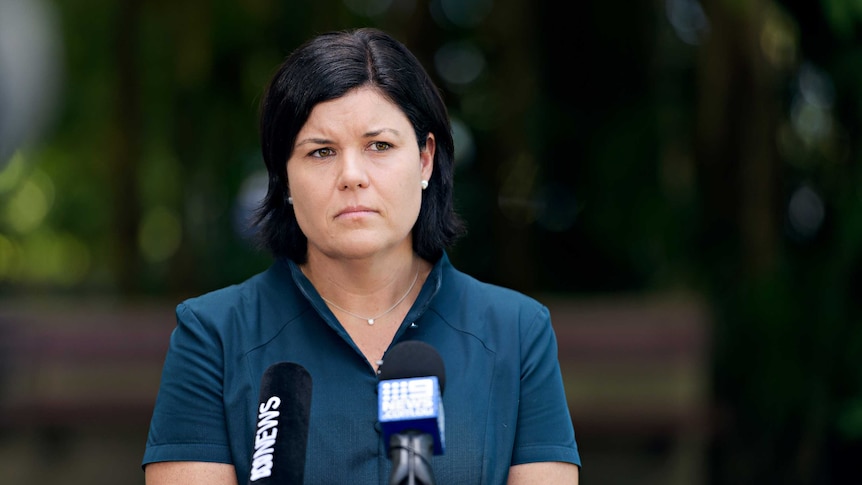 Natasha Fyles stands in front of microphones and looks serious.