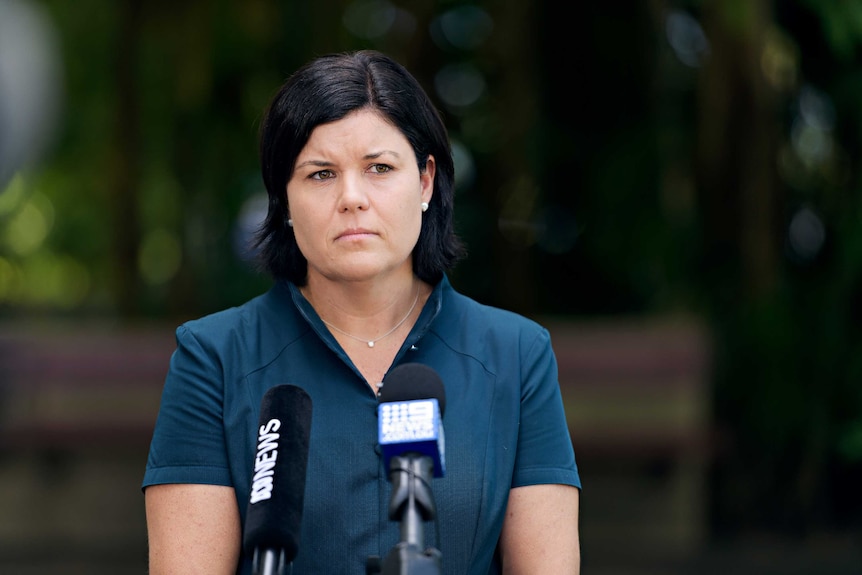 Natasha Fyles stands in front of micrphones and looks serious.