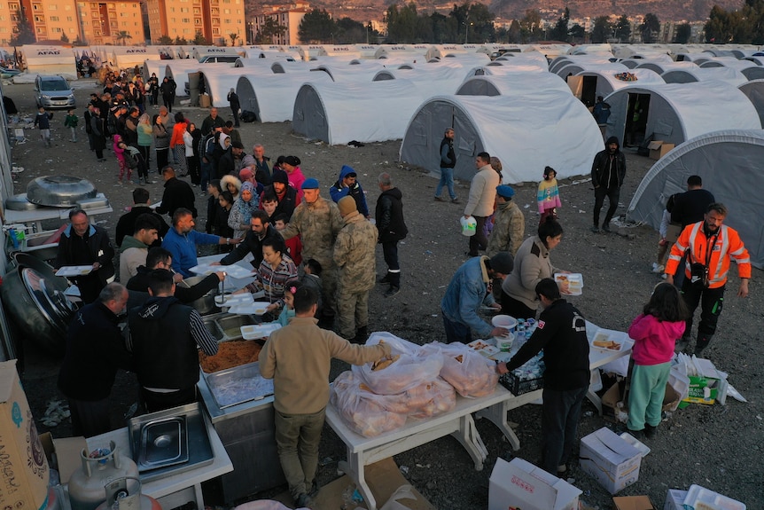 Le persone che hanno perso la casa nel devastante terremoto si mettono in fila per ricevere cibo in un accampamento improvvisato.