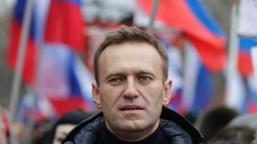 Alexei Navalny takes part in a march in front of Russian flags.