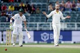 Nathan Lyon stands with his arms out, next to batsman Dean Elgar during a cricket match.
