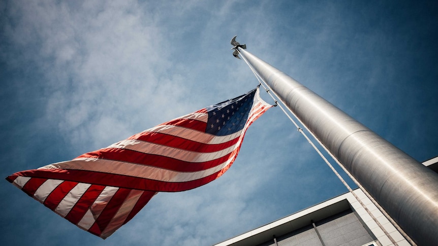 An American flag flies from a flagpole outside a building.