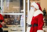 A man dressed as Santa wearing a face mask.