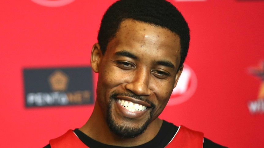 Perth Wildcats Bryce Cotton smiling in front of a red background