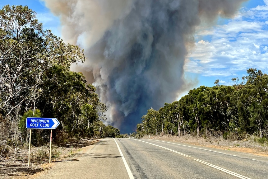 A golf club sign and bushfire in distance