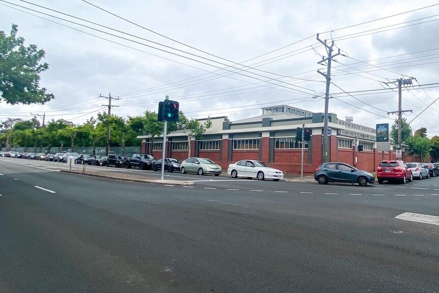 A queue of cars is parked up along and down a block.