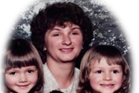 An old photo of a woman sitting with three young children.