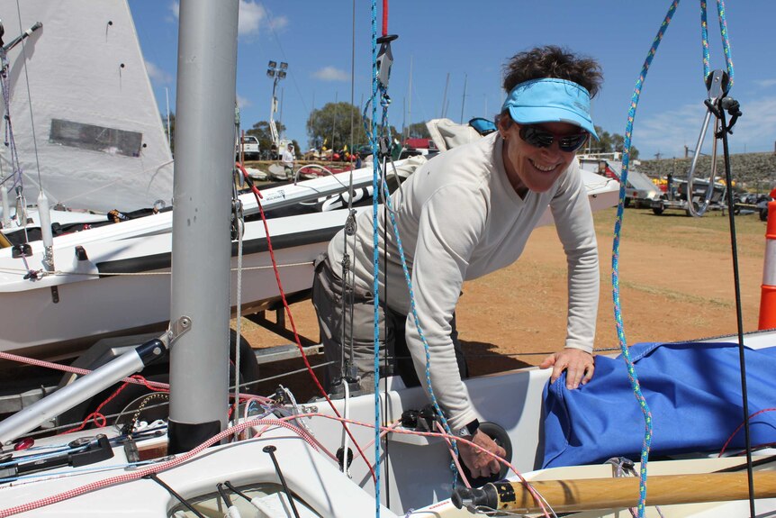 A woman adjusts equipment ahead of sailing.