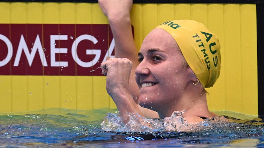 Australian swimming star Ariarne Titmus smiles and pumps her fist in celebration in the water at the end of a big race.