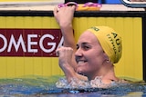 Australian swimming star Ariarne Titmus smiles and pumps her fist in celebration in the water at the end of a big race.