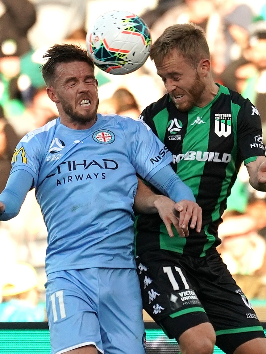 A Melbourne City A-League player and Western United opponent both attempt to head the ball in the air.