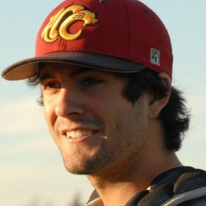 A man wearing a baseball cap smiles.