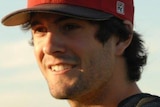 A man wearing a baseball cap smiles.