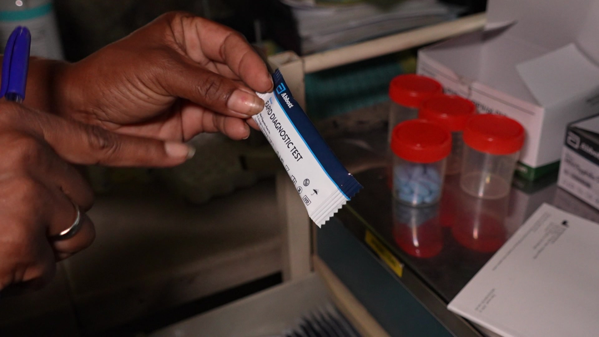 Una mujer sostiene una pequeña prueba rápida de VIH sin usar en un laboratorio