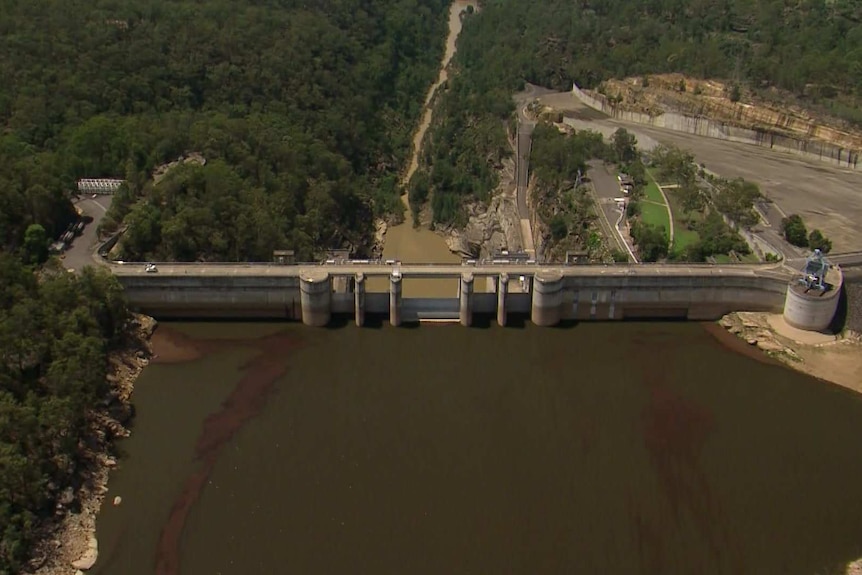 aerial vision of dark sediment next to a dam wall