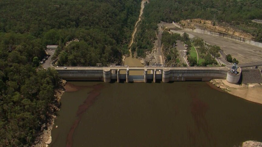 aerial vision of dark sediment next to a dam wall