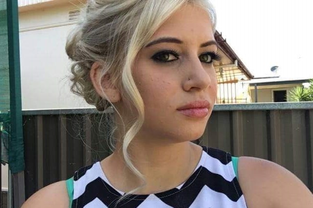 A teenage girl dressed up with makeup and hair styled.