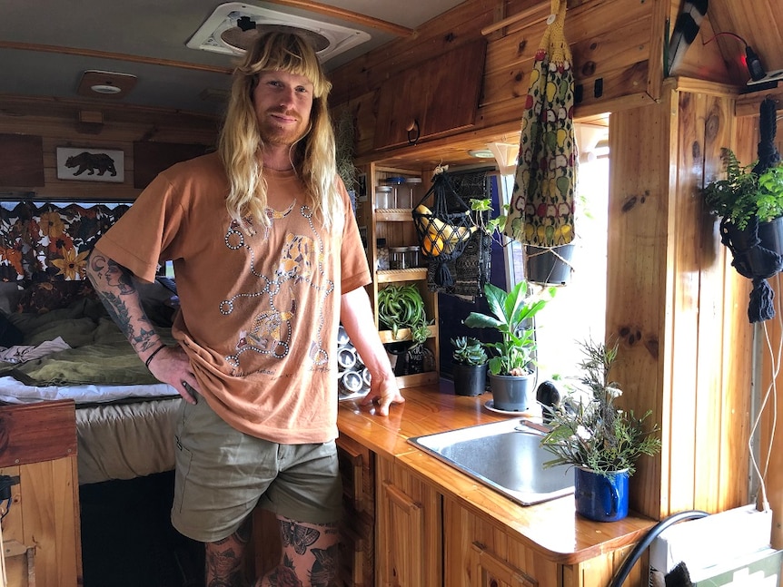 Professional board rider Nicky Gornall standing by the kitchen in his converted Coaster bus.