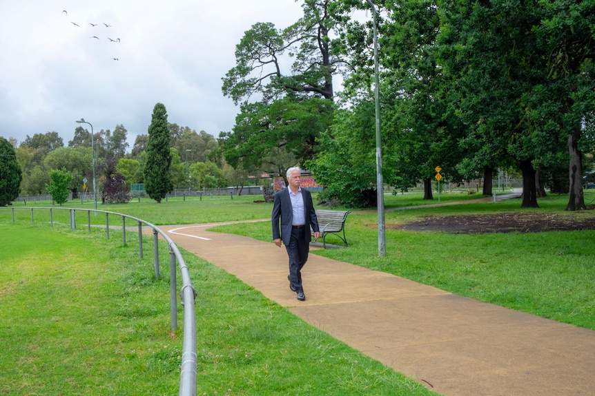 Chris O'Connor walks through a park.