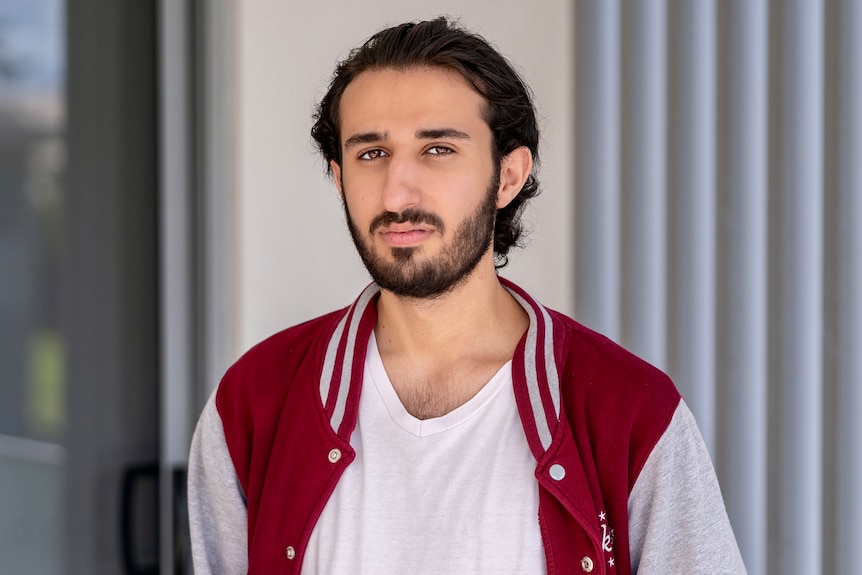 Hussein I'lachi wearing a maroon and white jacket staring directly into the camera. 