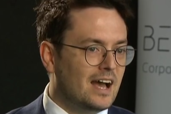 Man in glasses and business clothing with mouth open speaking.