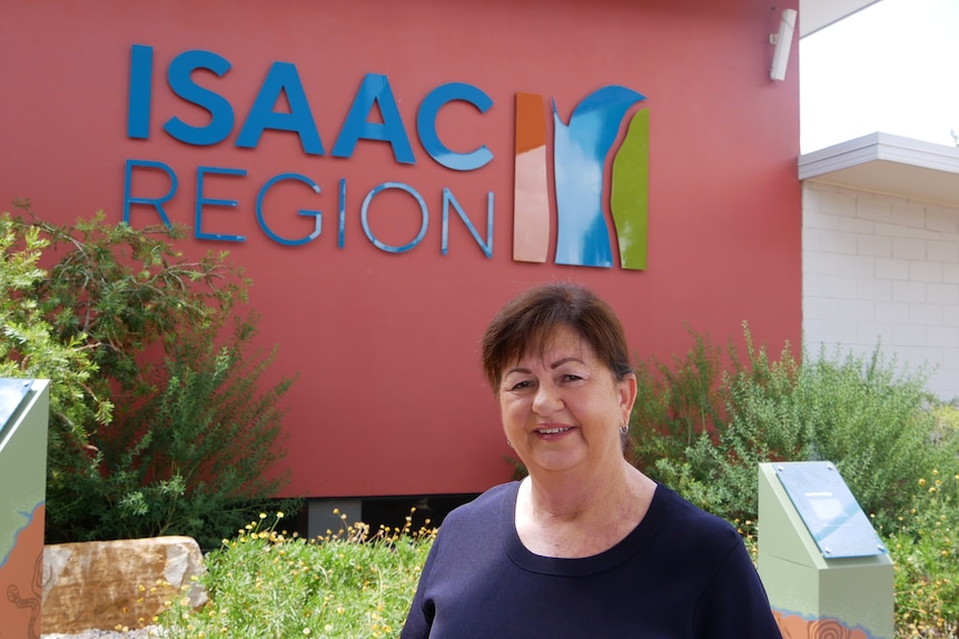 A woman with brown hair stands in front of a council building.