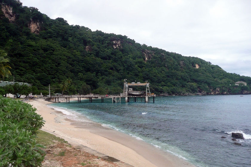 An ocean cove with a boat ramp, fringed by bright green vegetation.