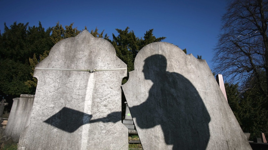 The shadow of a gravedigger on headstones