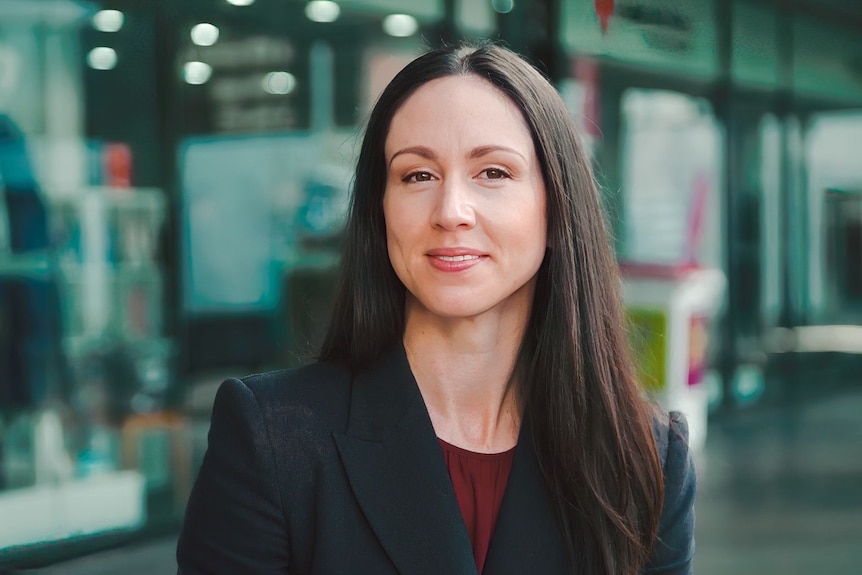 A woman in a suit smiles at the camera.