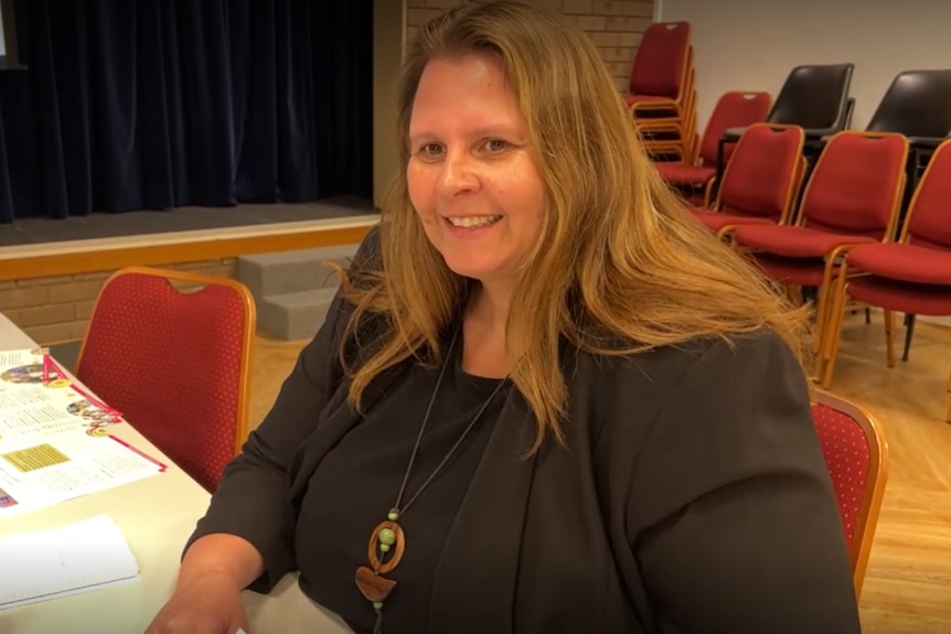 Brown haired woman wearing black seated at a table while conducting volunteer training