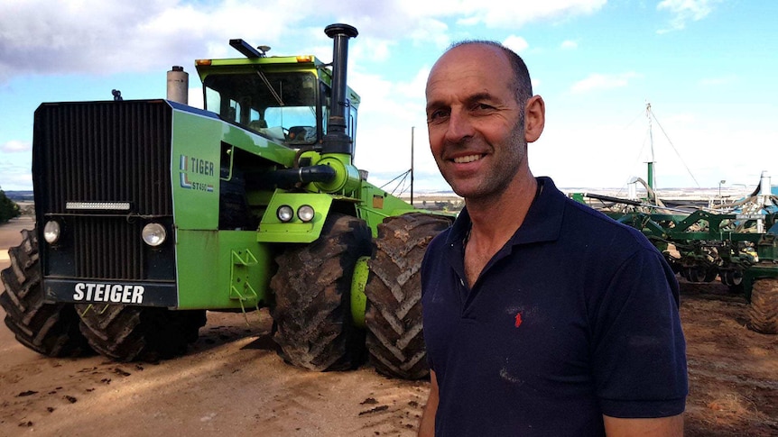 A man stands in front of a tractor