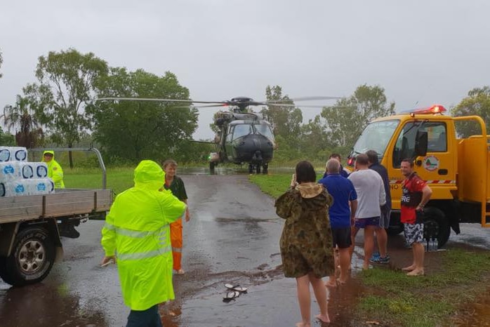 A helicopter is on the ground as people stand around in front of it.
