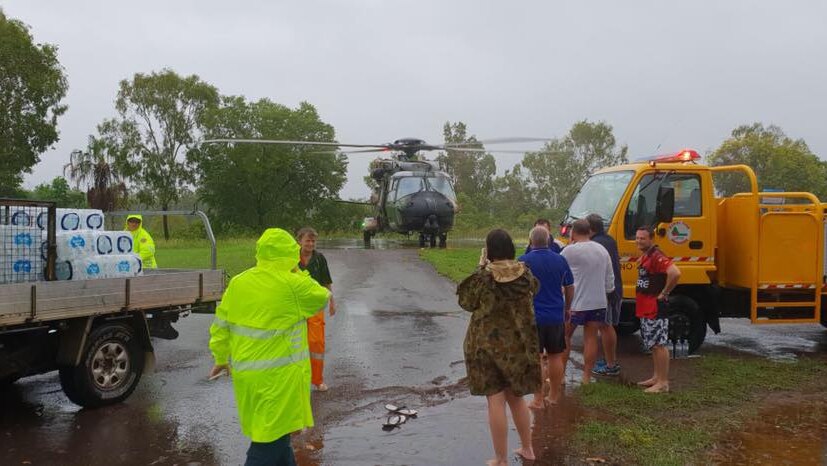A helicopter is on the ground as people stand around in front of it.