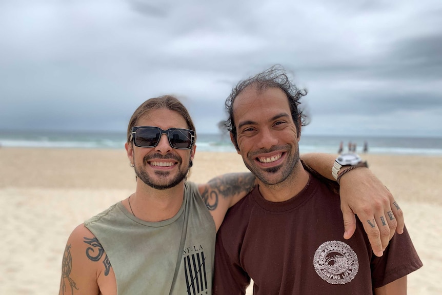 Two men at a beach, smiling.