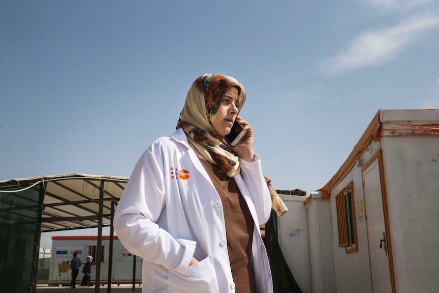 Dr Reema holds a phone to her ear outside the camp maternity clinic.
