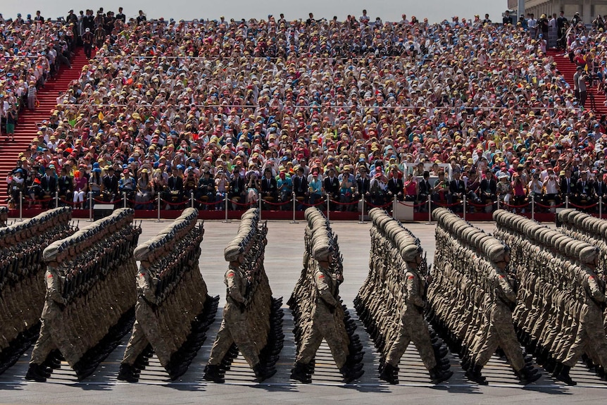 Chinese soldiers march in lockstep in front of a viewing crowd.