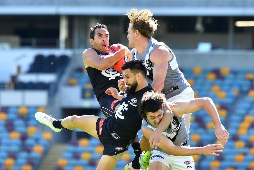 An AFL player grimaces as he takes a pack mark with other players colliding in mid-air.