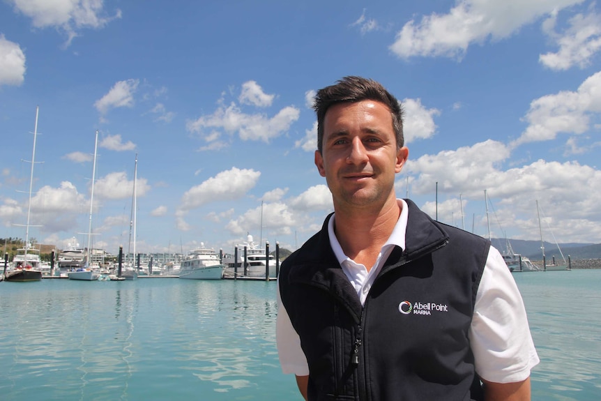 A man stands in front of a marina with docked boats