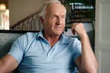 Greg Norman is speaking while sitting in a chair in his home