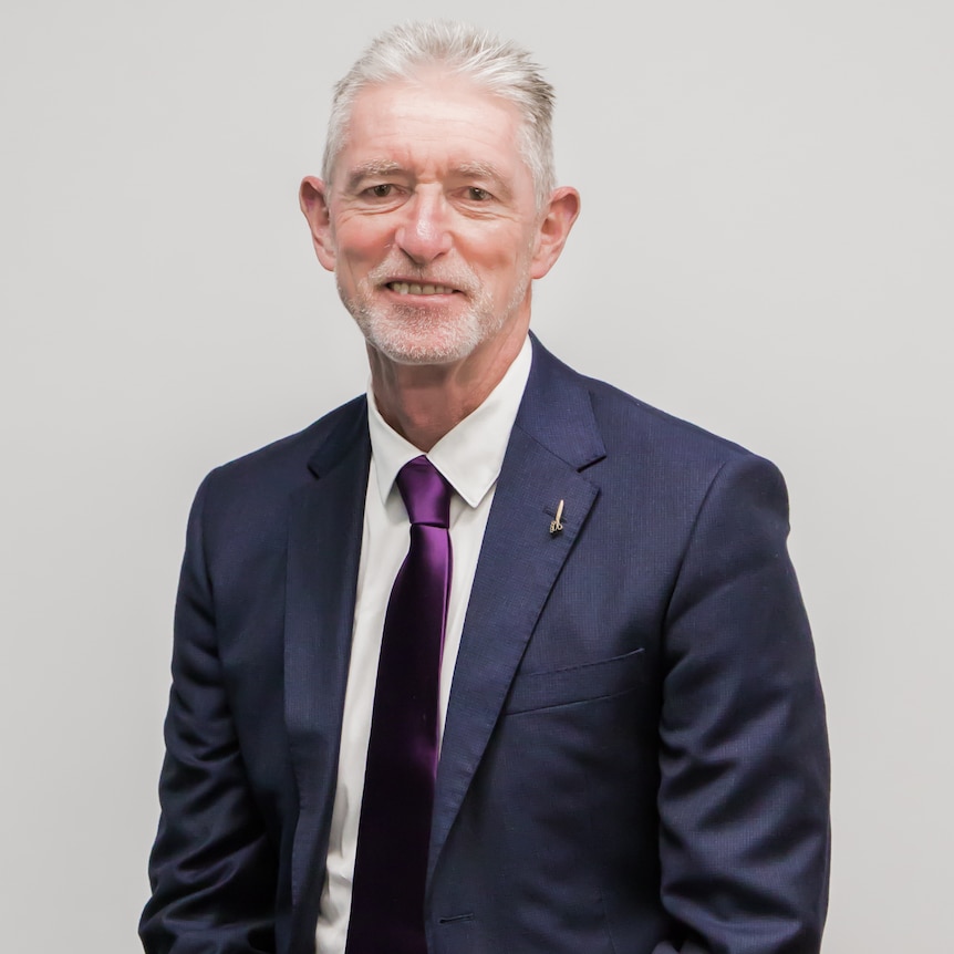 Man with white hair and beard wearing suit and tie