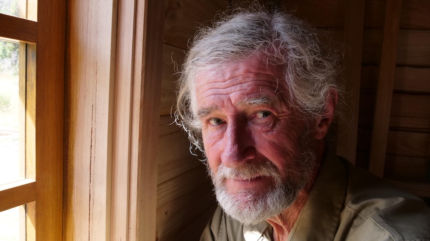 Close up of man with short beard nearby wooden framed window