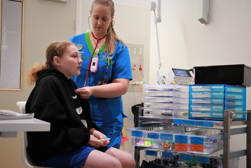 Toni Grayson holds sensory objects while being examined by a doctor.