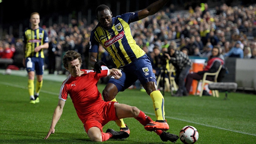 Usain Bolt is tackled while playing for the Central Coast Mariners in an A-League trial match.