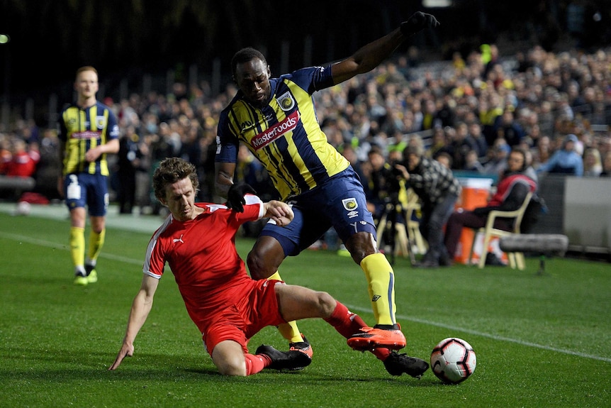 Usain Bolt is tackled while playing for the Central Coast Mariners in an A-League trial match.