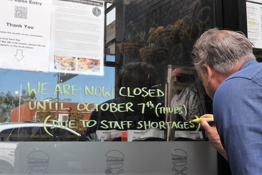 A man writes on a window.