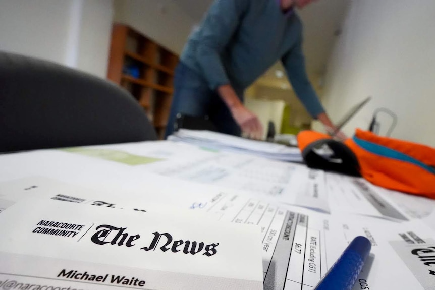 Michael Waite stands at his desk searching paperwork.