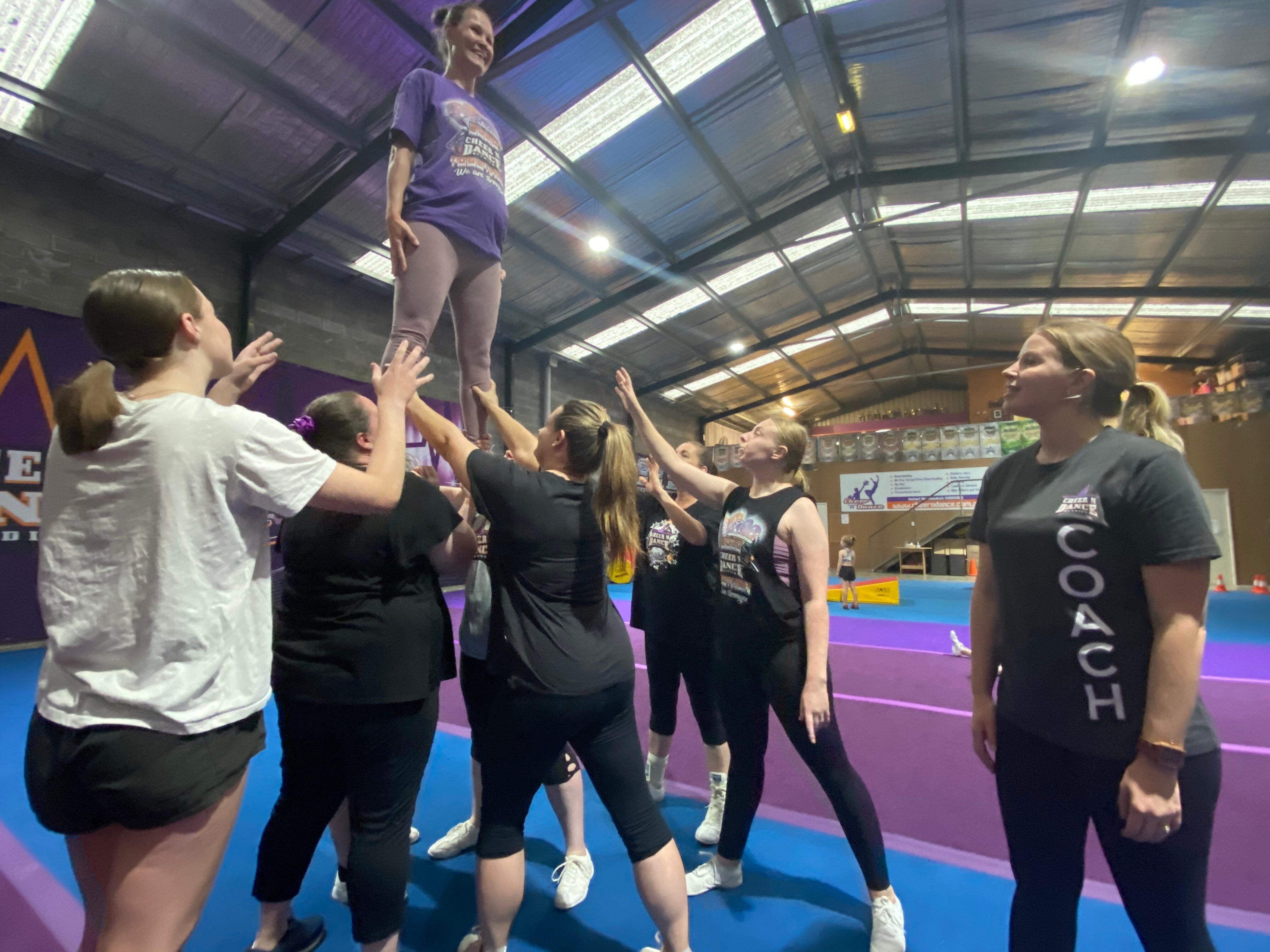 Six women holding up another woman who is standing. 