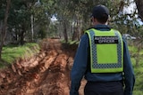 A Parks Victoria enforcement officer looks at a damaged clay track.