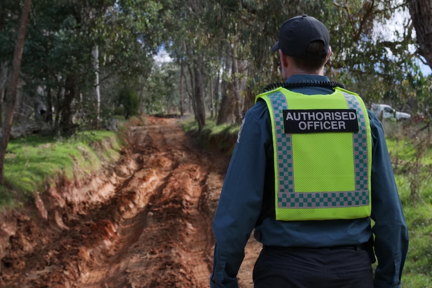 A Parks Victoria enforcement officer looks at a damaged clay track